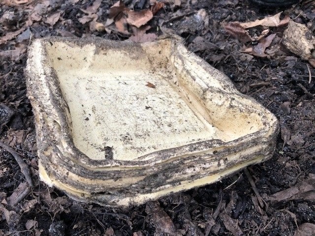 Decomposing stack of food trays sitting on compost pile