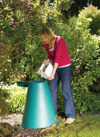 Woman using a green cone for backyard food scraps